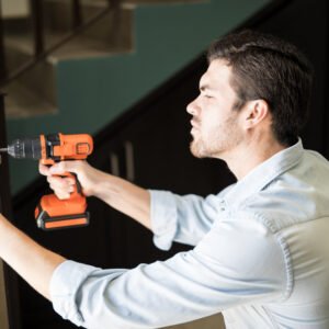 A man standing at his front door, holding the doorknob with worry as he checks the lock multiple times before leaving.